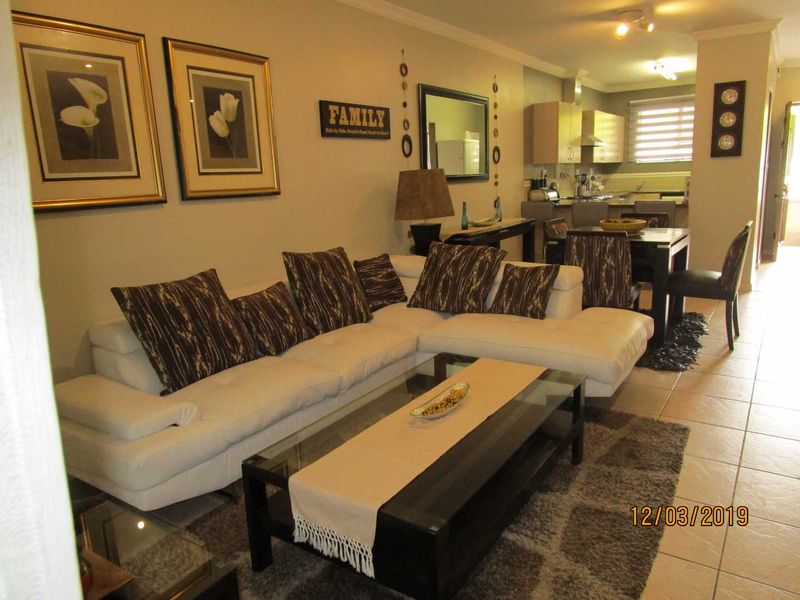 Open-plan living and dining area featuring tiled flooring and a connected kitchen with built-in cabinetry and integrated appliances.