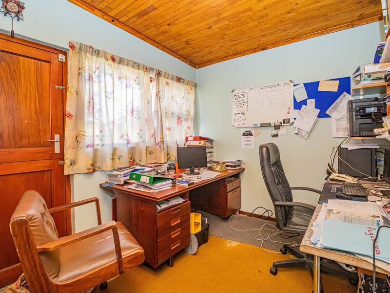 A functional home office space featuring a timber-clad ceiling and solid wood door, offering a practical area for work or study.
