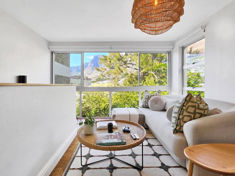 Bright living room featuring large windows with scenic mountain views, clean white walls, and a modern open-plan layout.