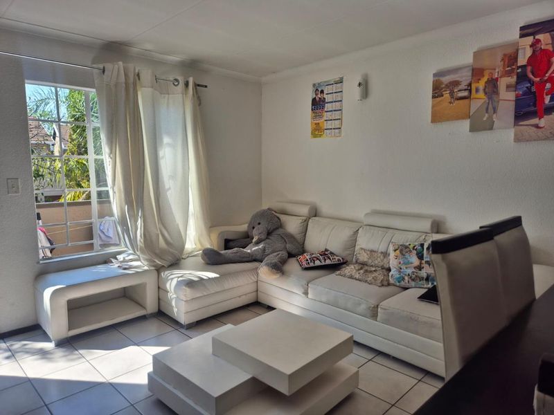 A bright living room featuring tiled flooring and a large window that allows for ample natural light.
