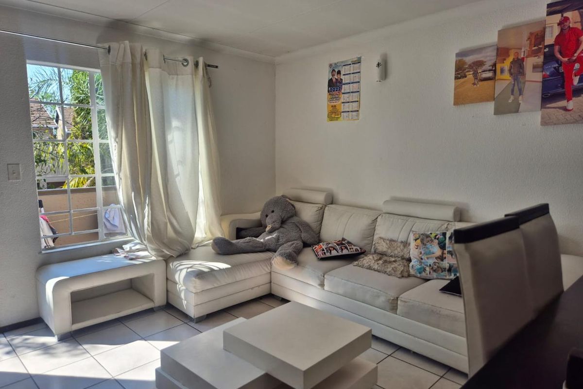 A bright living room featuring tiled flooring and a large window that allows for ample natural light.