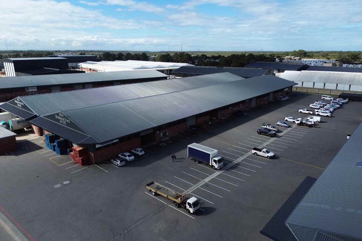 Aerial view of a commercial business park featuring large warehouse units with metal roofing, paved parking areas, and designated loading zones.