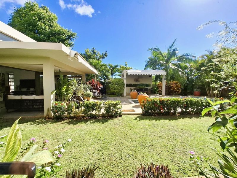 A well-maintained rear garden featuring a covered patio, a swimming pool with a poolside gazebo, and established landscaping.