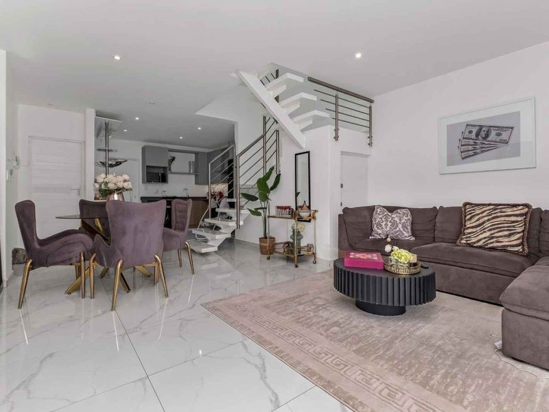 Modern open-plan living and dining area featuring polished marble-look flooring, recessed lighting, and a contemporary open-tread staircase with stainless steel railings.