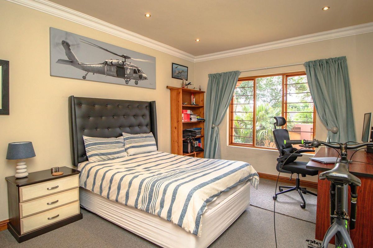 A well-maintained bedroom featuring neutral walls, crown molding, recessed lighting, and a large window providing natural light and garden views.