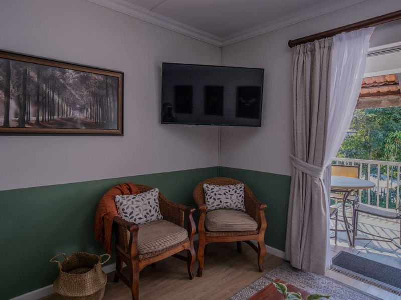 A cozy living area featuring laminate flooring, crown molding, and a sliding glass door providing direct access to an outdoor balcony.