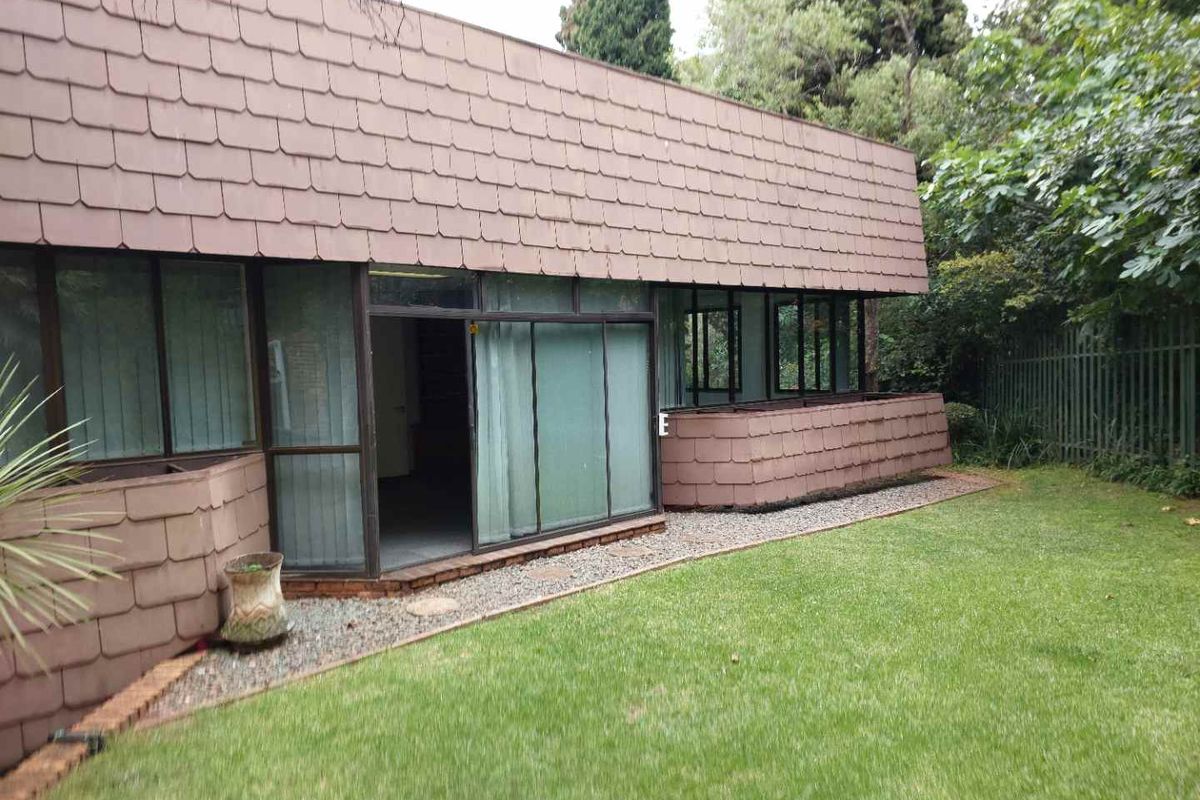 Rear view of the office building featuring a tiled facade, large sliding glass doors, and access to a private garden area.