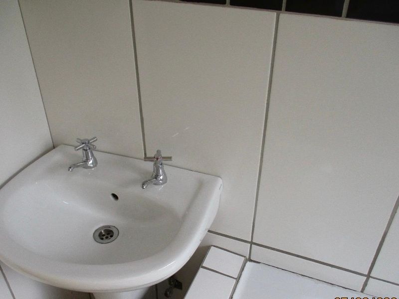 A close-up view of a bathroom pedestal basin featuring chrome taps and tiled wall finishes.