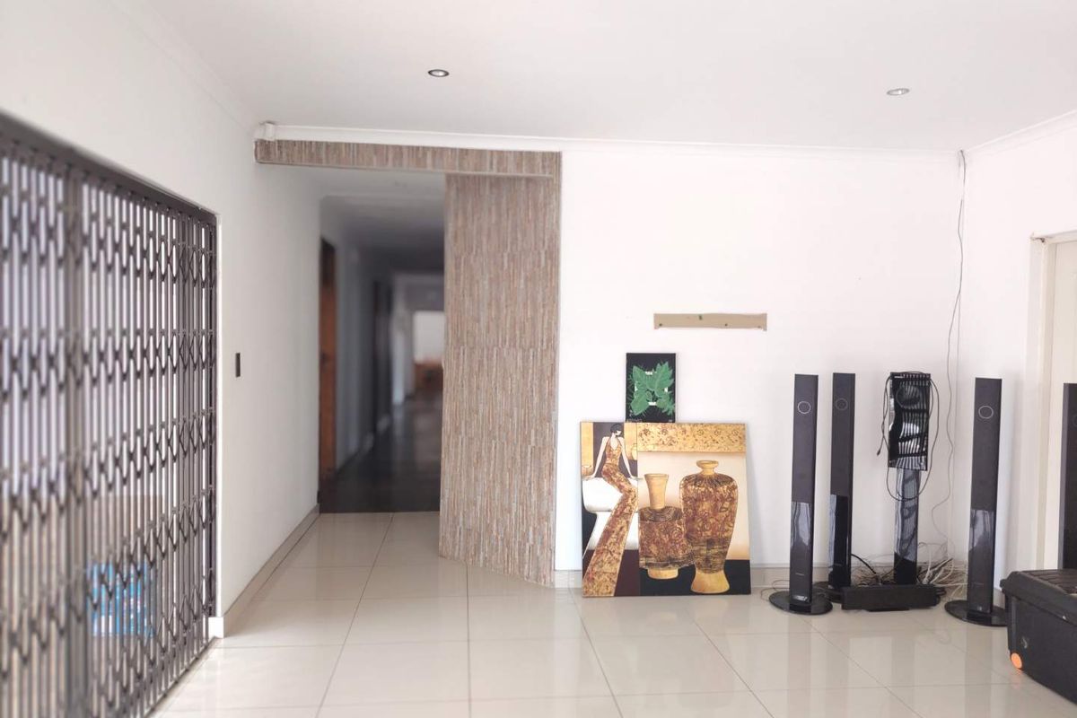 A bright living area featuring tiled flooring, recessed downlighting, and a decorative wood-look feature panel leading into the hallway.
