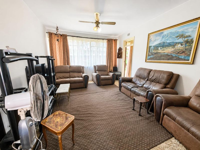 A spacious living room featuring a ceiling fan and large window, providing natural light and access to the rest of the apartment.