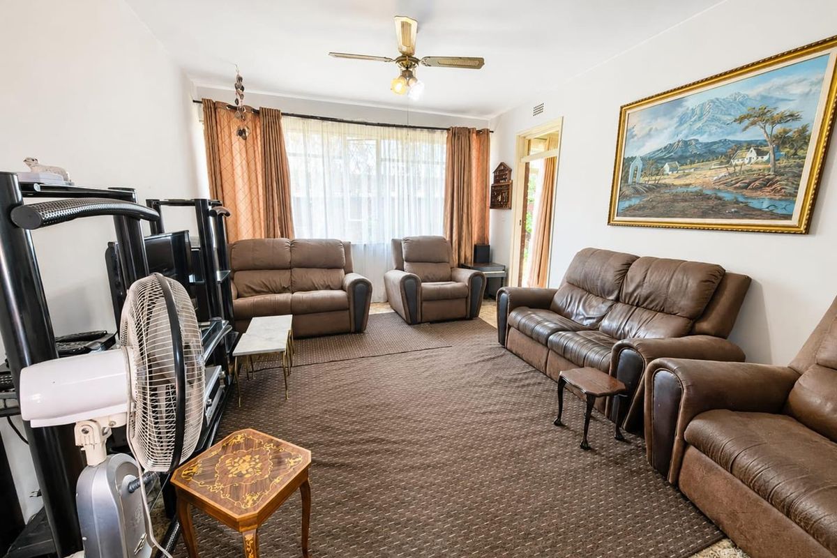 A spacious living room featuring a ceiling fan and large window, providing natural light and access to the rest of the apartment.