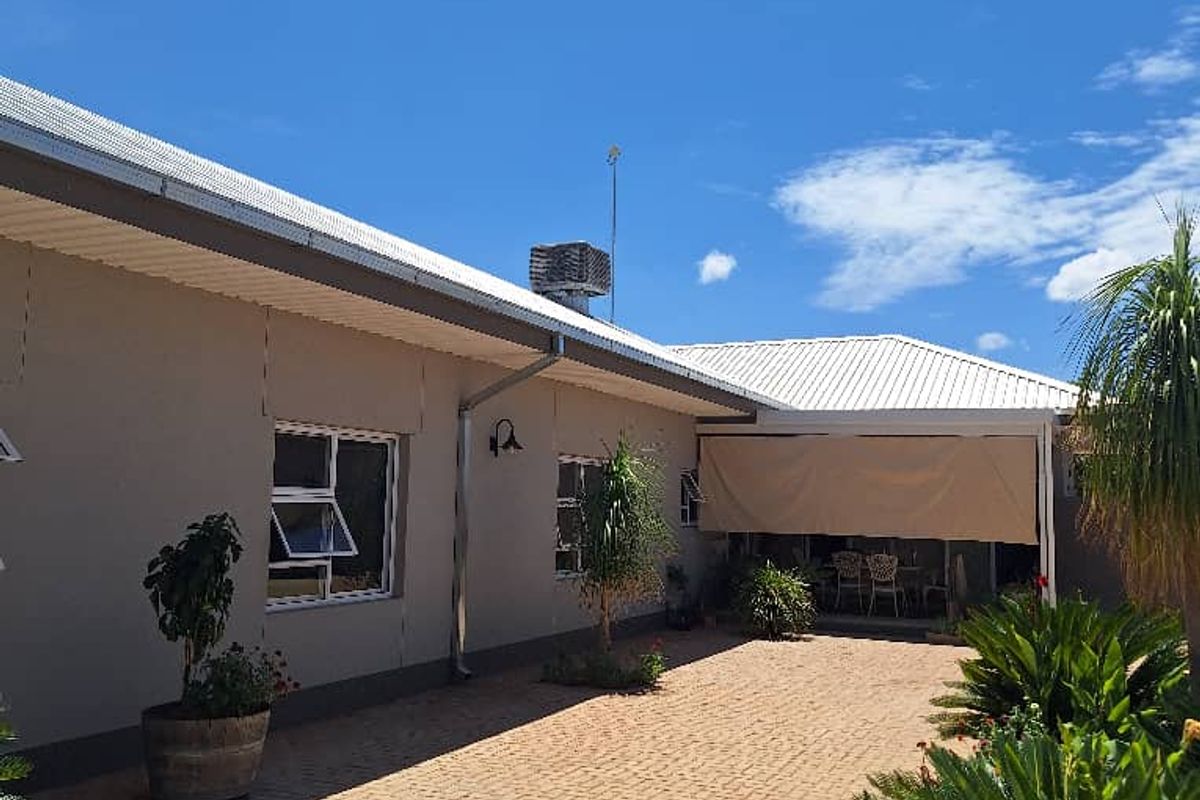 A view of the rear exterior of the farm property, featuring a paved courtyard, covered patio area, and well-maintained building facade.