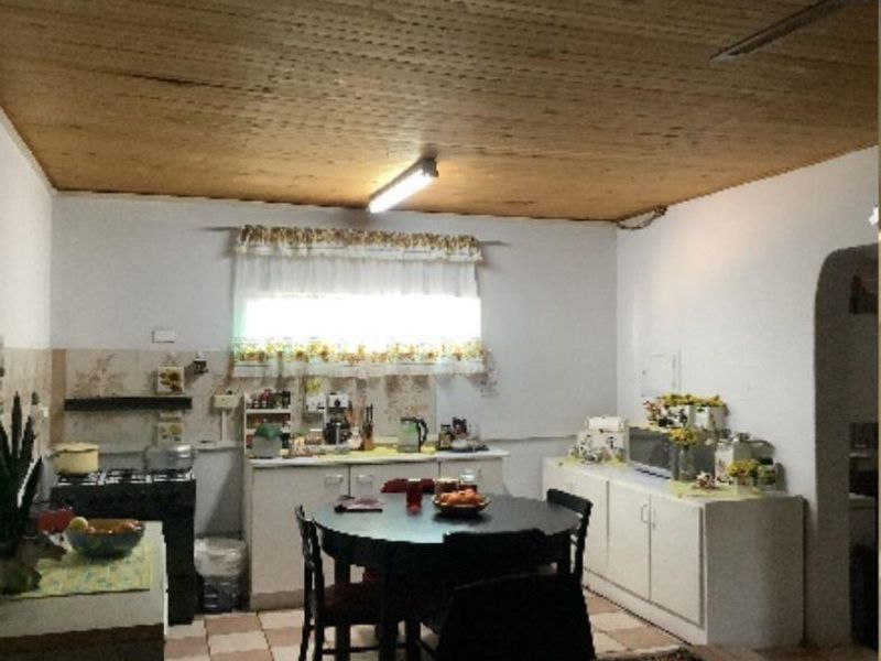 A dated kitchen featuring timber ceilings, tiled backsplash, and built-in cabinetry with a functional layout suitable for modernization.