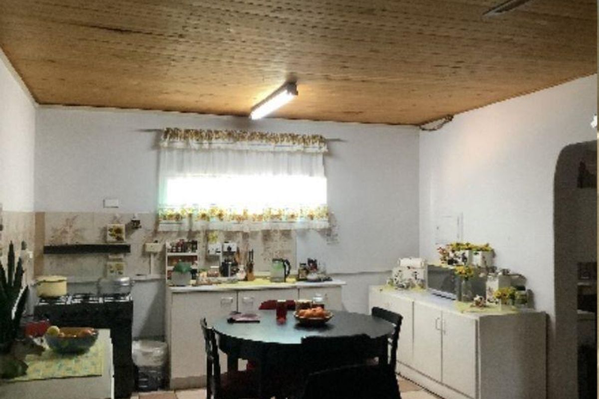 A dated kitchen featuring timber ceilings, tiled backsplash, and built-in cabinetry with a functional layout suitable for modernization.
