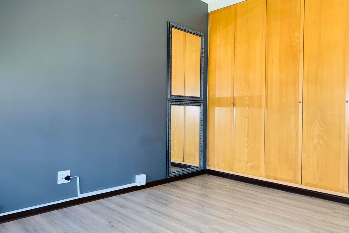 Bedroom featuring light wood-look flooring, a dark accent wall, and built-in wooden cabinetry providing ample storage space.