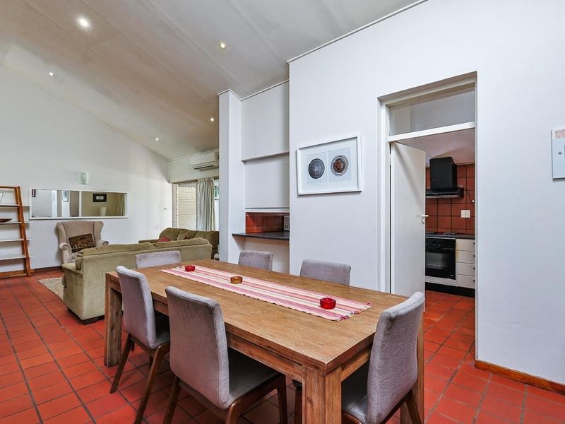 Open-plan living and dining area featuring vaulted ceilings, terracotta floor tiles, recessed lighting, and direct access to a separate scullery.