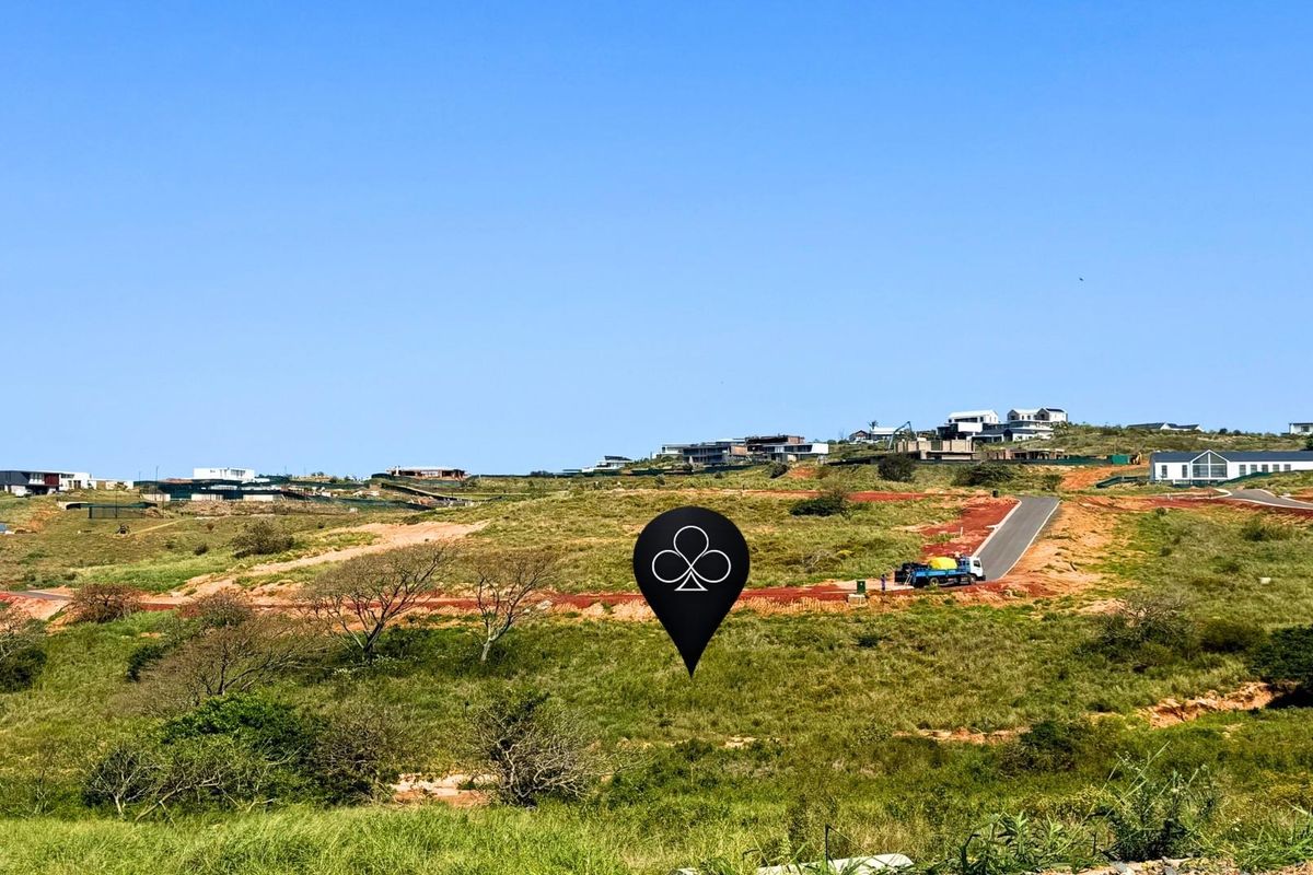 An aerial view of a vacant residential plot featuring natural landscape and access to a paved road within a developing estate.