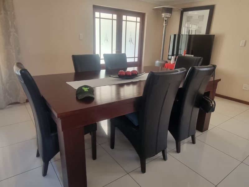 A dining room featuring large format floor tiles, neutral wall finishes, and double french doors providing natural light.