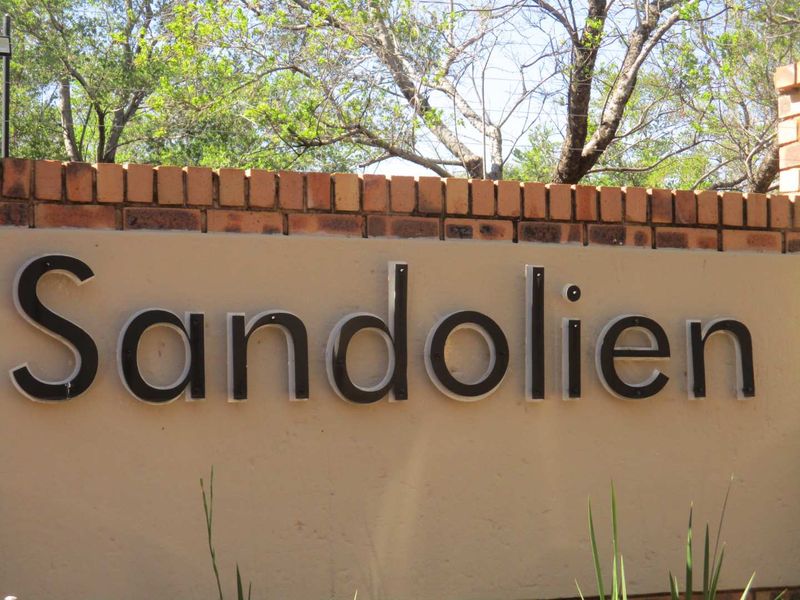 A clear view of the Sandolien complex signage mounted on a brick boundary wall.