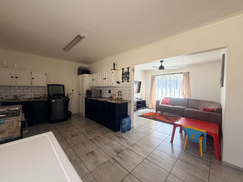 Open-plan kitchen and living area featuring tiled flooring, white and black cabinetry, and a subway tile backsplash.