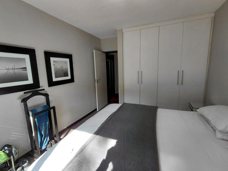 A functional bedroom featuring neutral wall tones and ample built-in cupboard storage space.