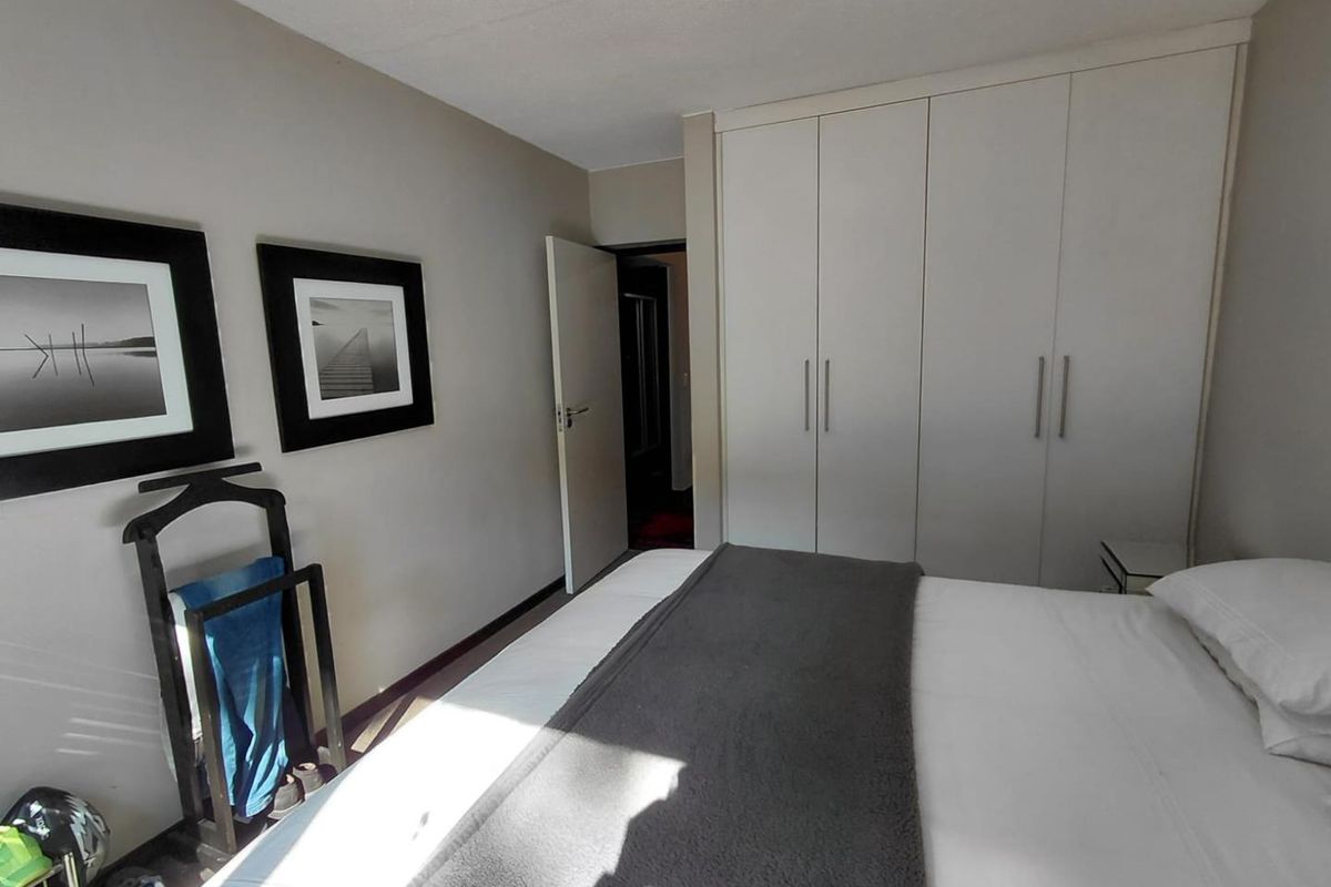 A functional bedroom featuring neutral wall tones and ample built-in cupboard storage space.