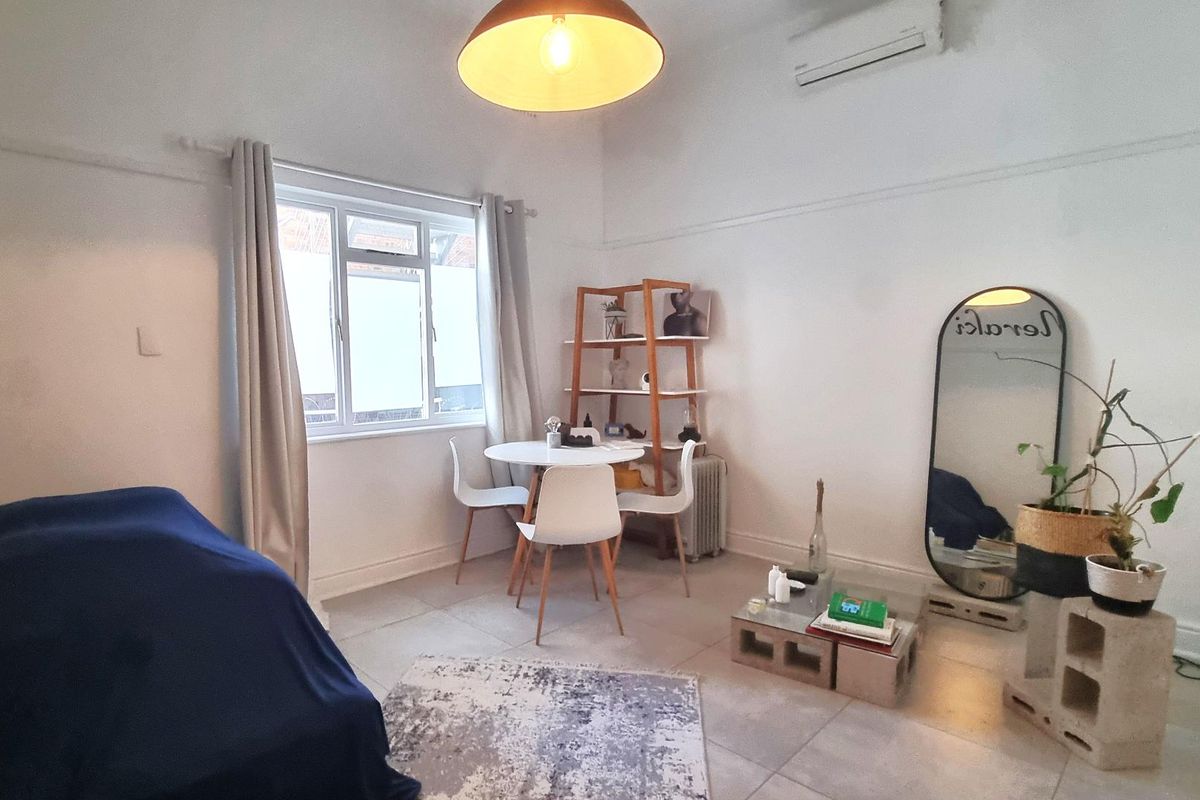 A bright living area featuring tiled flooring, a wall-mounted air conditioning unit, and a classic picture rail detail.