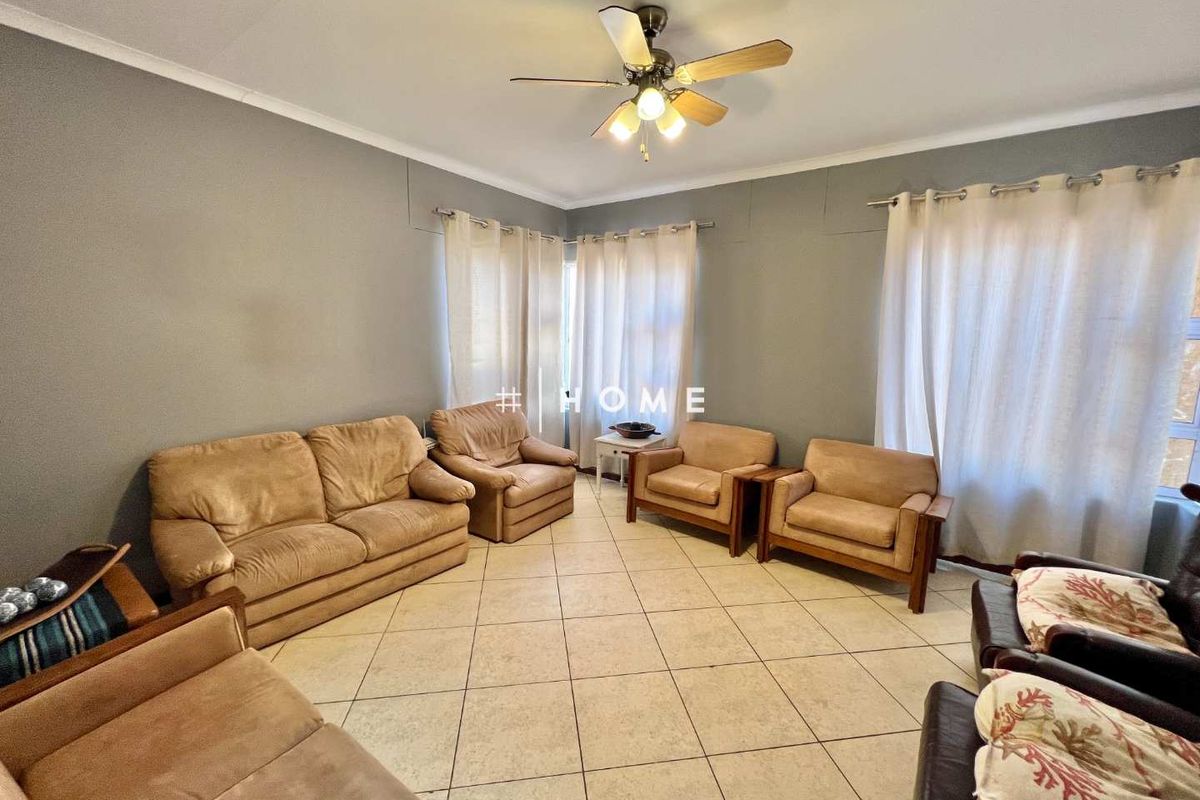 A spacious living room featuring neutral grey walls, tiled flooring, and a ceiling fan, offering a comfortable and functional layout.