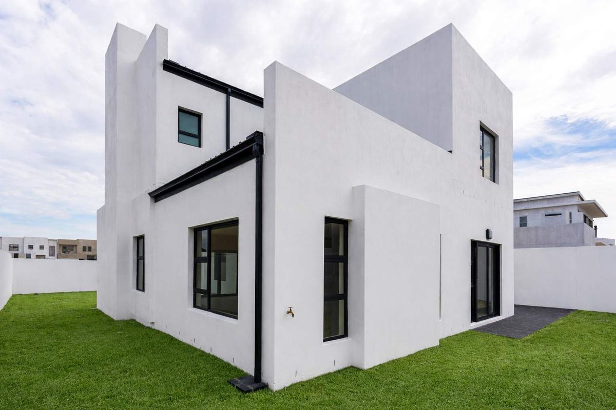 A modern two-story residential property featuring clean white exterior walls, black window frames, and a well-maintained surrounding lawn.