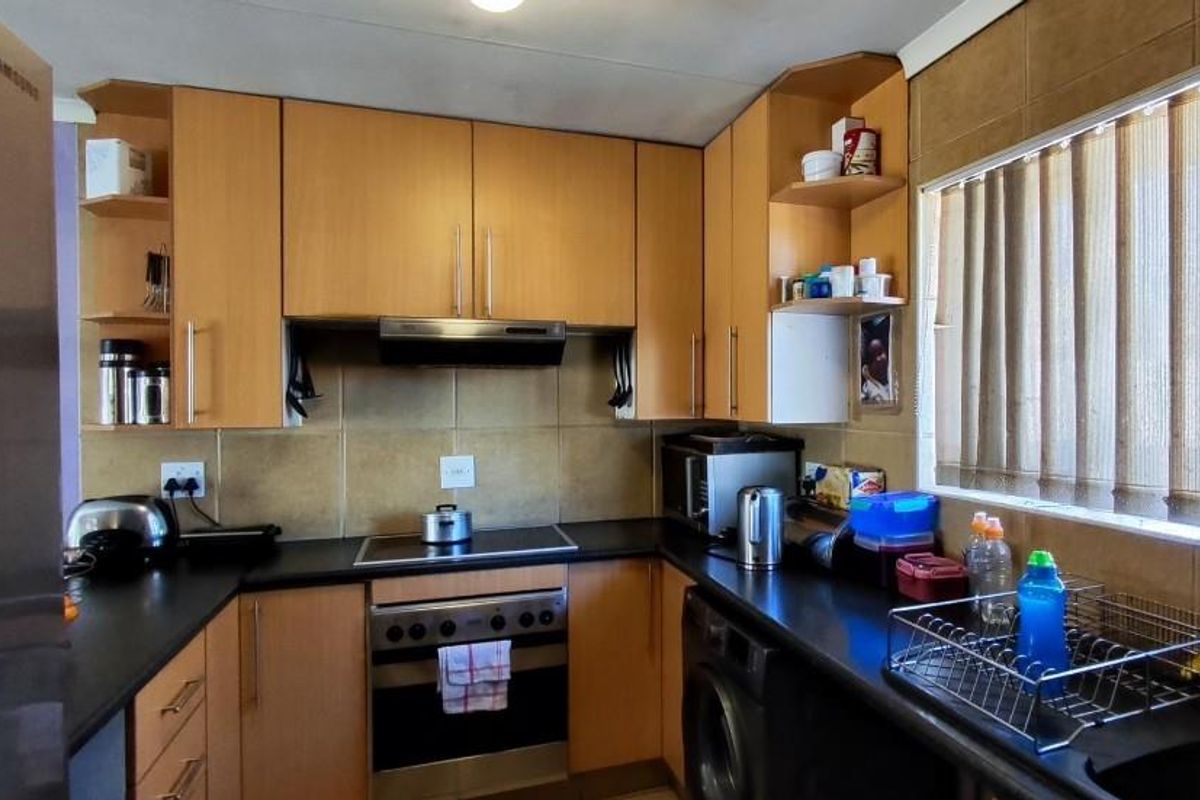 A functional kitchen featuring light wood cabinetry, dark countertops, a built-in oven with extractor fan, and tiled splashbacks.