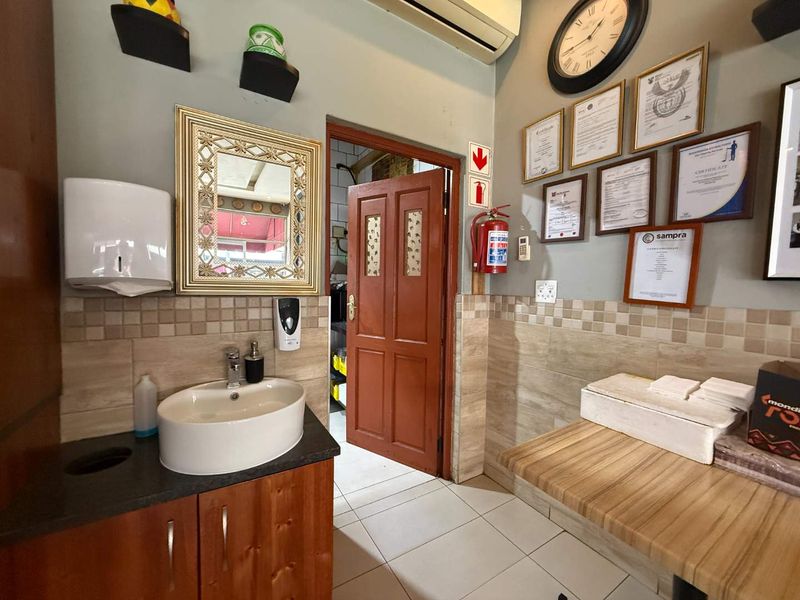 A functional utility area featuring a vanity with a vessel sink, tiled backsplash, and essential safety equipment including a fire extinguisher.