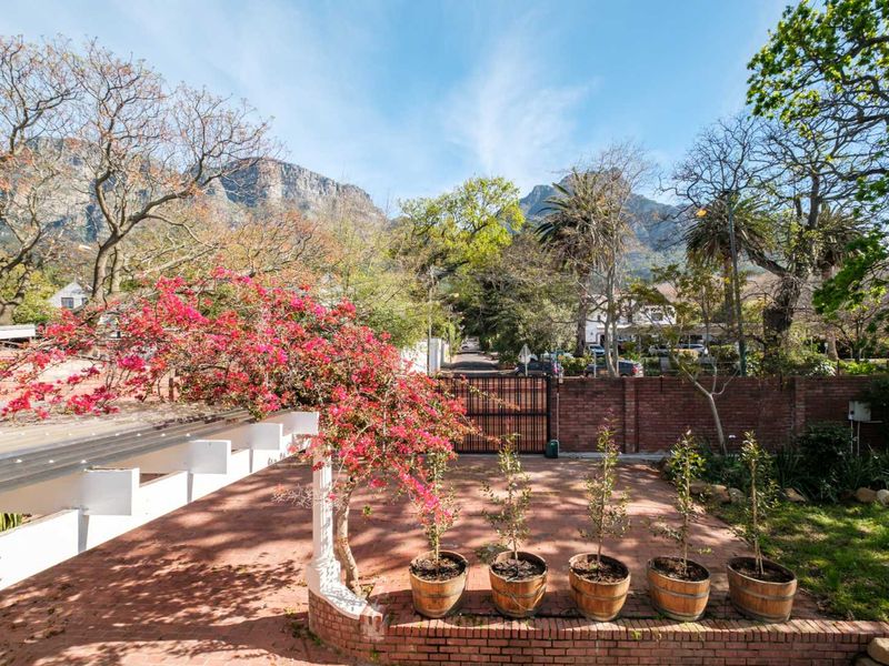 A paved outdoor patio area featuring a pergola, brick boundary wall, and mountain views, providing a pleasant space for outdoor relaxation.
