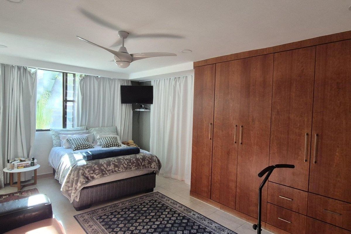 A well-maintained bedroom featuring extensive built-in wooden cabinetry, a ceiling fan, and recessed lighting, providing ample storage and a comfortable living space.
