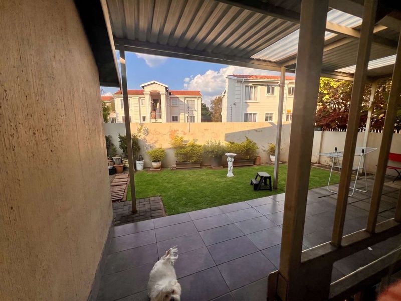 A covered patio area with tiled flooring overlooking a private garden with a perimeter boundary wall.