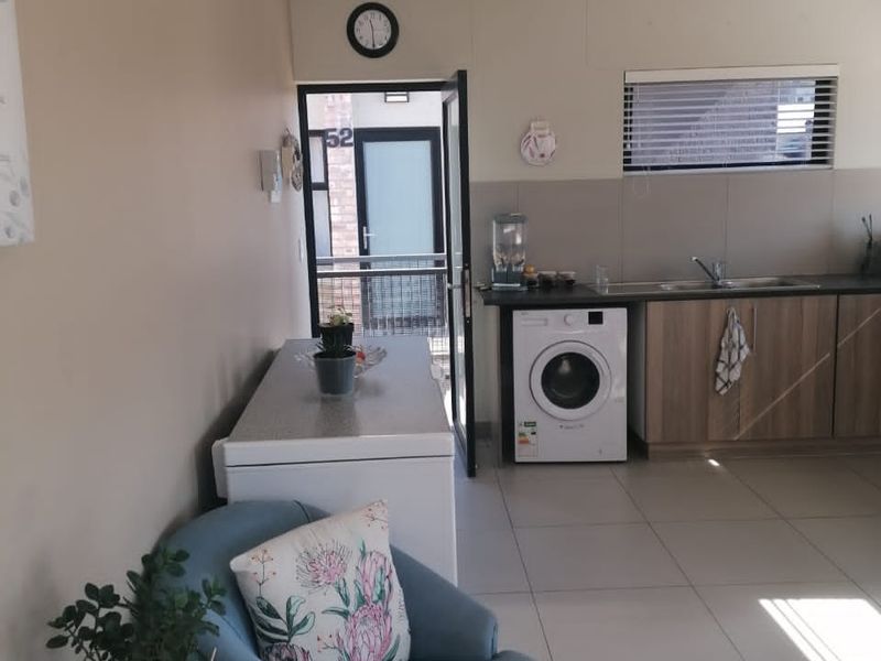 Open plan kitchen and living area featuring tiled flooring, built-in cabinetry, and a dedicated laundry space with an integrated washing machine.