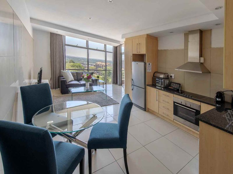 Modern open-plan apartment featuring a sleek kitchen with granite countertops, integrated appliances, and bright living area with expansive windows offering scenic views.