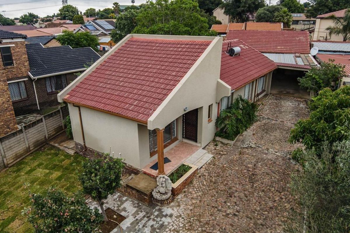 Aerial view of a residential property featuring a pitched tiled roof, paved driveway, and established garden area.
