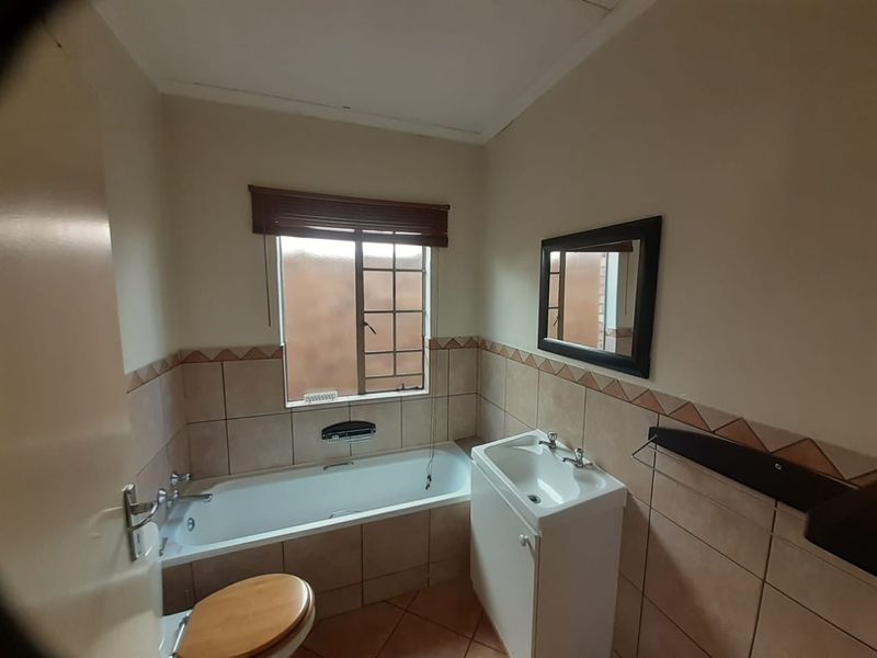 A functional bathroom featuring a built-in bathtub, a vanity cabinet with a basin, and tiled wall finishes.