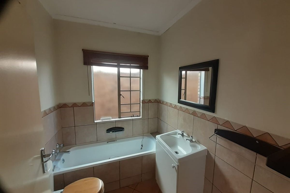 A functional bathroom featuring a built-in bathtub, a vanity cabinet with a basin, and tiled wall finishes.
