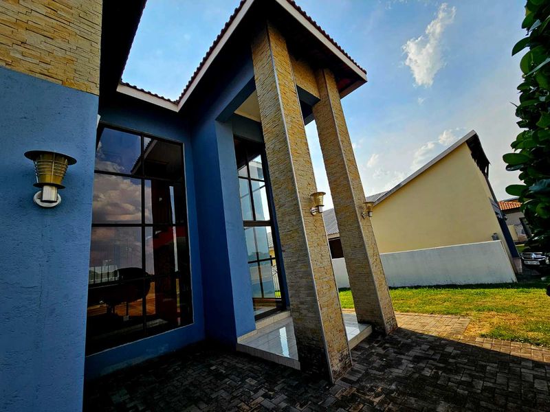A modern front entrance featuring stone cladding, large glass windows, and a paved driveway area.