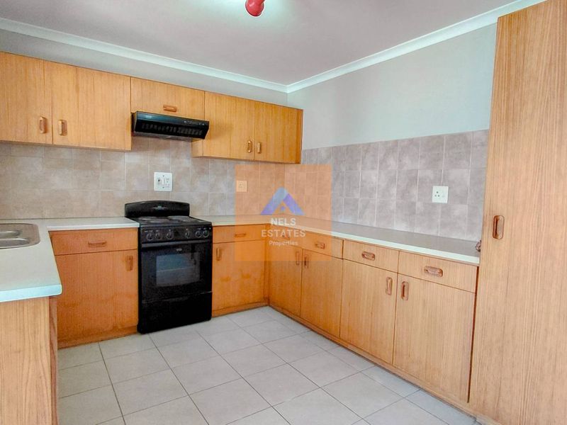 A functional kitchen featuring laminate cabinetry, tiled backsplash, built-in oven with extractor fan, and tiled flooring.