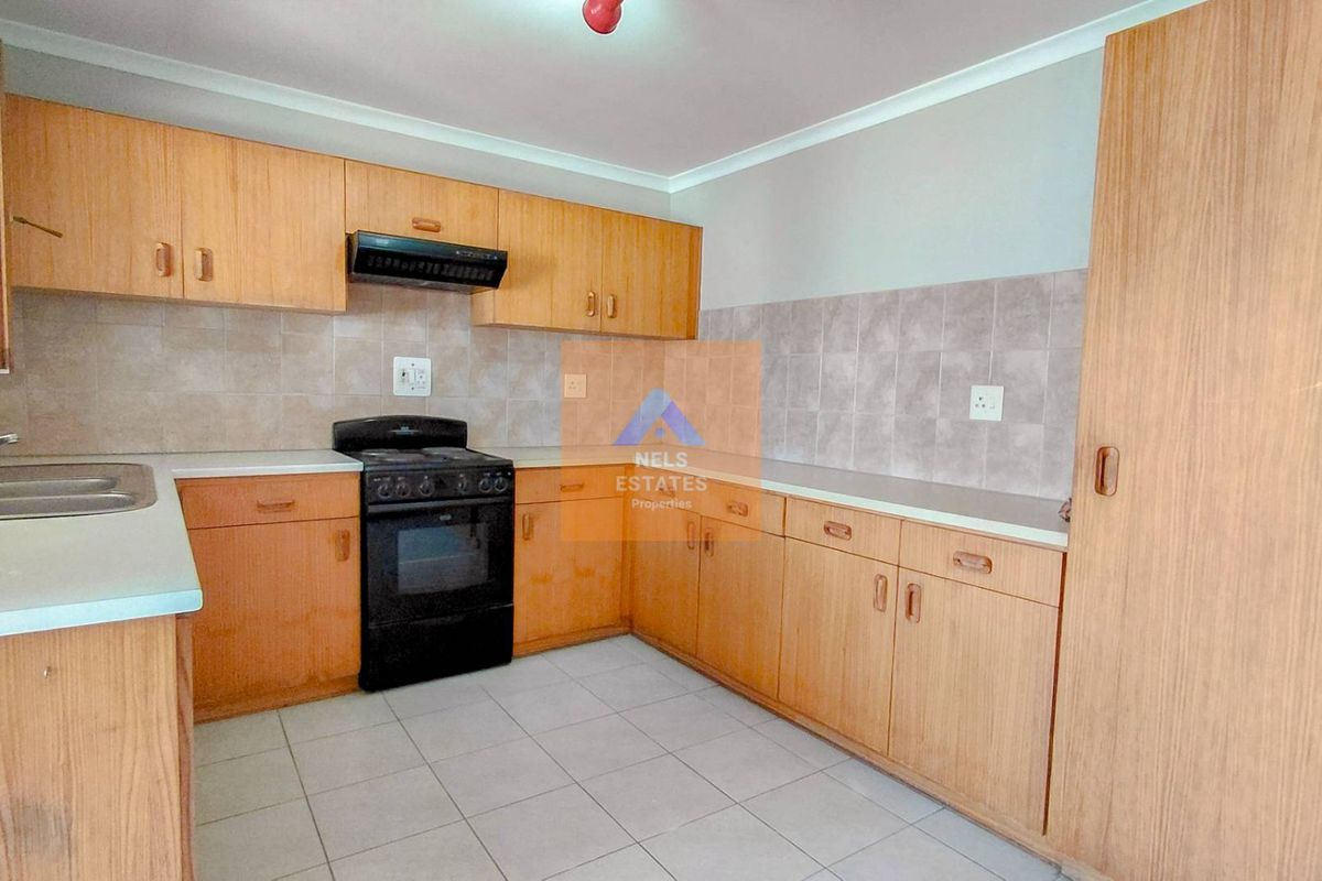 A functional kitchen featuring laminate cabinetry, tiled backsplash, built-in oven with extractor fan, and tiled flooring.