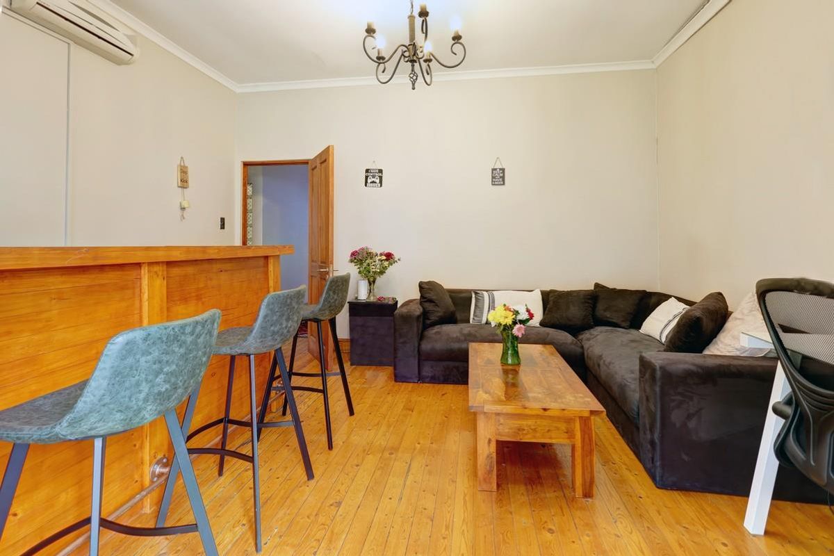 A living room featuring timber flooring, a built-in wooden bar counter, and a wall-mounted air conditioning unit.