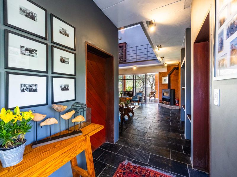 Welcoming entrance hall featuring slate flooring, exposed concrete ceilings, and a wood-burning fireplace, leading into an open-plan living area.