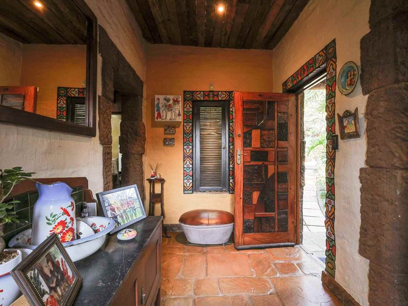 Welcoming entrance hall featuring rustic terracotta floor tiles, exposed timber ceiling beams, and a distinctive solid wood front door with decorative detailing.