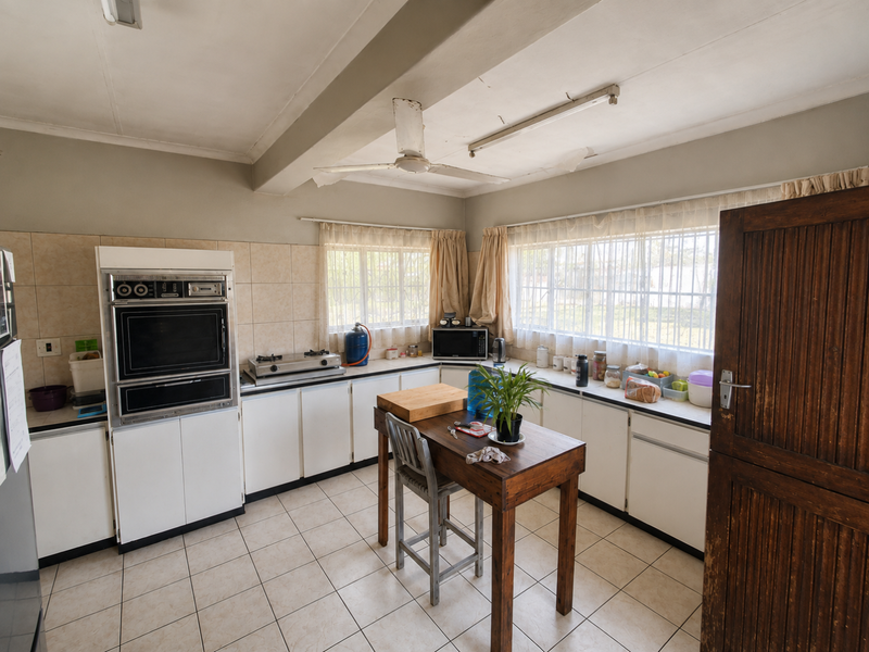 A dated kitchen featuring white cabinetry, tiled flooring, and a built-in oven, with visible signs of wear on the ceiling and cabinetry.