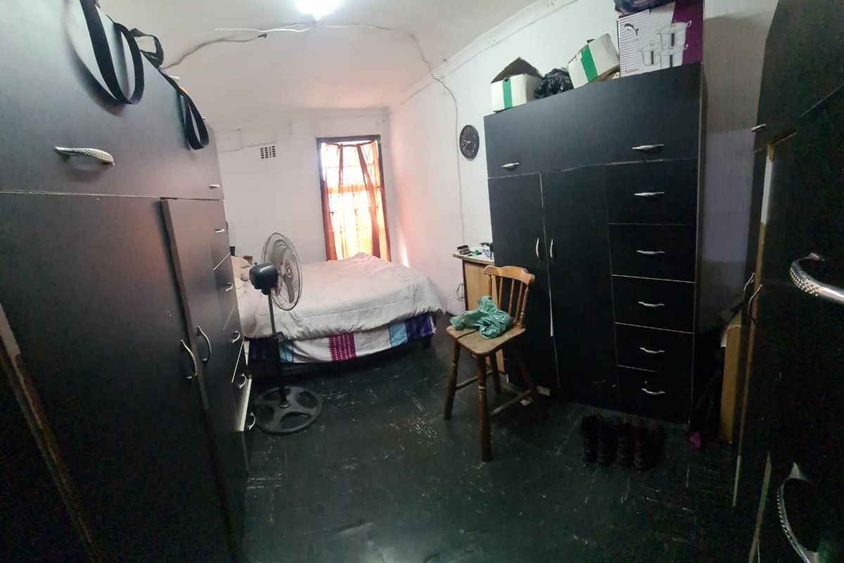 A bedroom featuring dark flooring and a ceiling with visible cracks, requiring maintenance and cosmetic updates.
