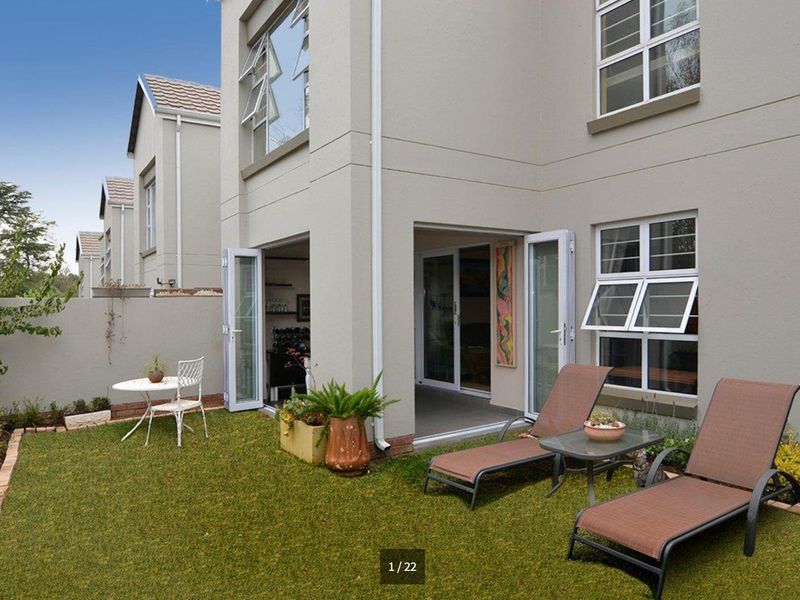Rear view of a double-storey cluster home featuring a private garden, lawn area, and direct access through double-leaf glass doors.
