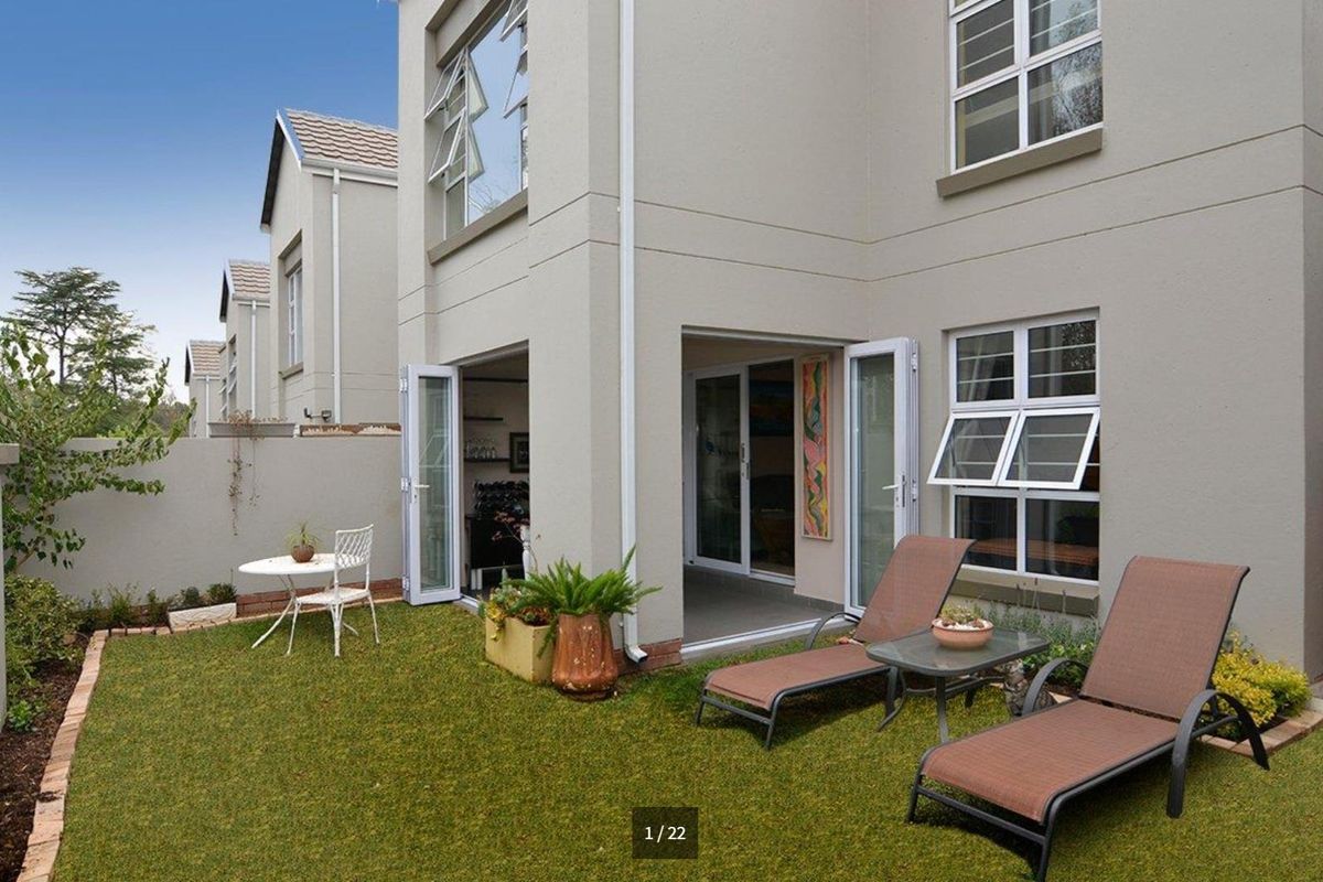 Rear view of a double-storey cluster home featuring a private garden, lawn area, and direct access through double-leaf glass doors.