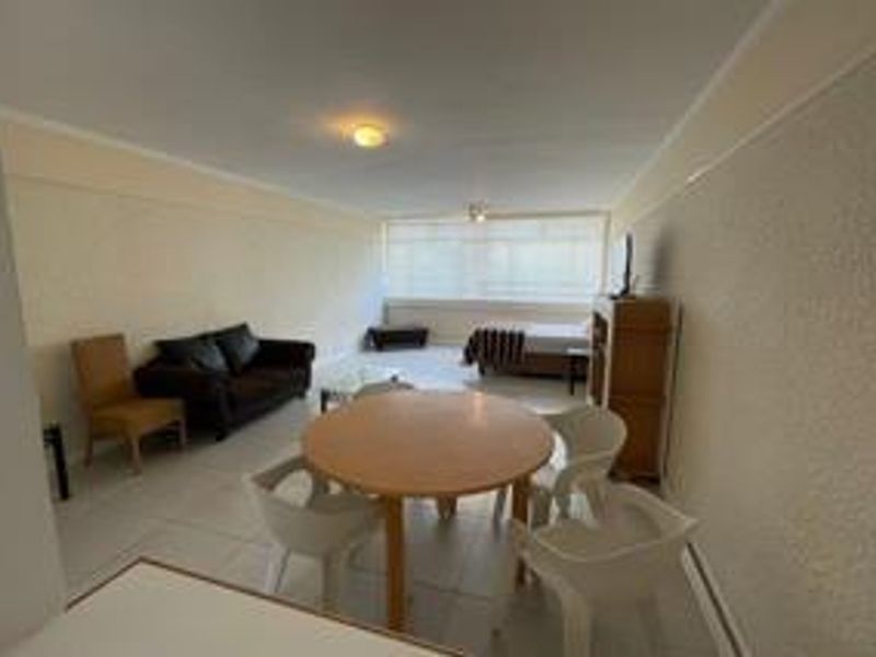 An open-plan living and dining area featuring tiled flooring and neutral wall finishes, providing a functional space for relaxation and meals.